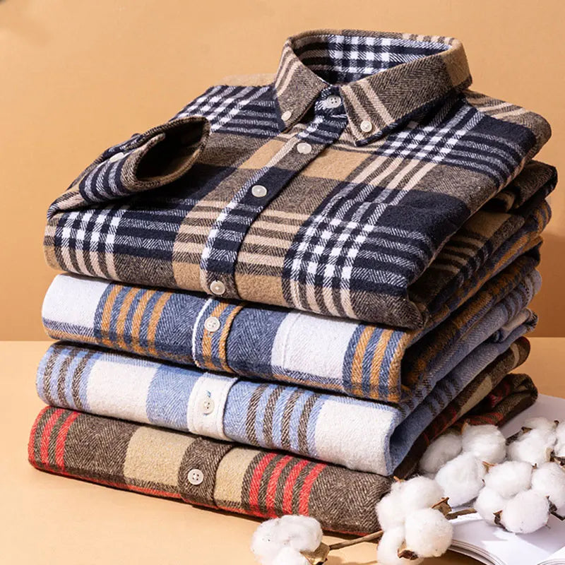 Stack of folded plaid shirts on a beige background with cotton branches.