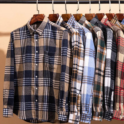 Row of plaid shirts on hangers against a beige background